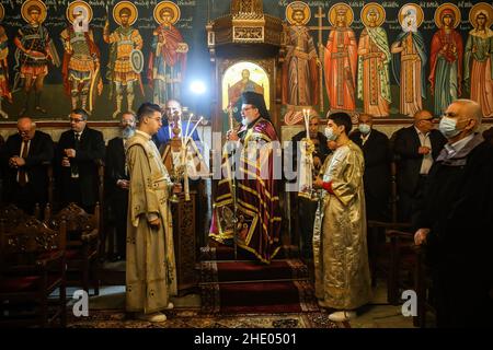 Un sacerdote conduce la messa alla chiesa greco-ortodossa di San Porphyrios. La maggior parte dei credenti ortodossi festeggia il Natale il 7 gennaio. Le chiese in Romania, Bulgaria, Cipro e Grecia lo segnano il 25 dicembre insieme ad altre denominazioni cristiane. Foto Stock