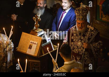 Un sacerdote conduce la messa alla chiesa greco-ortodossa di San Porphyrios. La maggior parte dei credenti ortodossi festeggia il Natale il 7 gennaio. Le chiese in Romania, Bulgaria, Cipro e Grecia lo segnano il 25 dicembre insieme ad altre denominazioni cristiane. Foto Stock