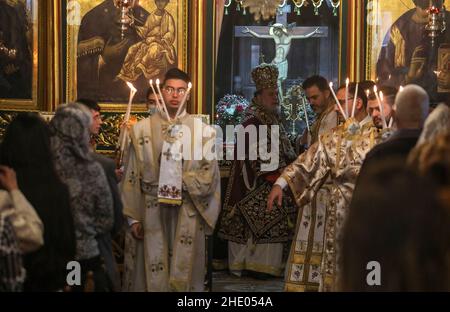 Un sacerdote conduce la messa alla chiesa greco-ortodossa di San Porphyrios. La maggior parte dei credenti ortodossi festeggia il Natale il 7 gennaio. Le chiese in Romania, Bulgaria, Cipro e Grecia lo segnano il 25 dicembre insieme ad altre denominazioni cristiane. Foto Stock