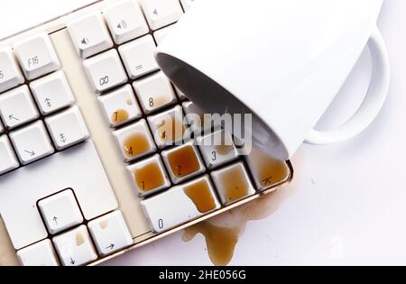 Il caffè si spillano sulla tastiera bianca del computer Foto Stock