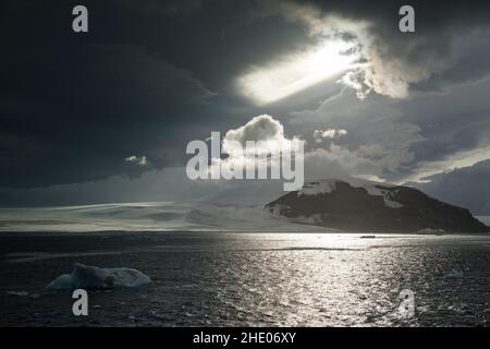 Il sole splende attraverso le nuvole spesse sull'Antartide. Foto Stock