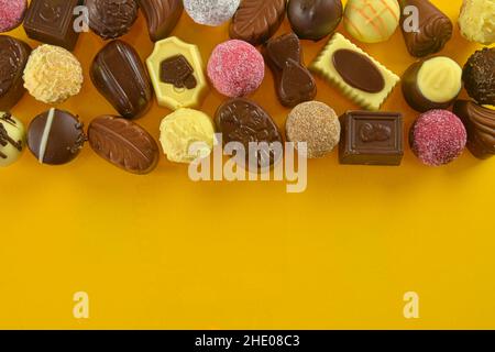 Biscotti al cioccolato e praline per un evento di vacanza su sfondo giallo con ampio spazio per le copie. Disposizione piatta Foto Stock