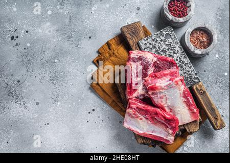 Manzo costolette di vitello kalbi, carne cruda su tavola macellaio in legno. Sfondo grigio. Vista dall'alto. Spazio di copia Foto Stock