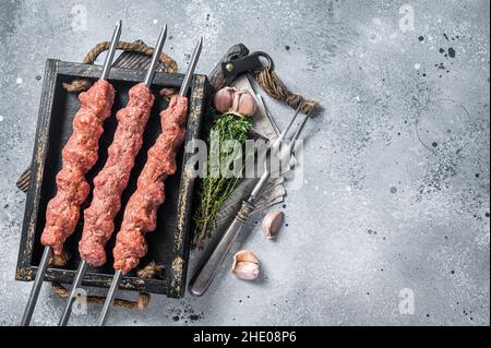 Shish kebab di carne di manzo e di agnello trito crudo, kebab adana turco. Sfondo grigio. Vista dall'alto. Spazio di copia Foto Stock