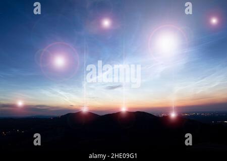 Un concetto di fantascienza. Di luci incandescenti UFO che galleggiano sopra le colline e una città appena prima dell'alba. Foto Stock