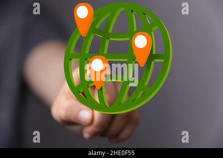 Una mano che punta a un rendering digitale di un globo con posizioni arancioni contrassegnate Foto Stock
