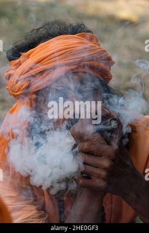 KOLKATA, BENGALA OCCIDENTALE, INDIA. 7th Jan 2022. Un sadhu sta fumando al campo di transito di Gangasagar, Kolkata. I preparativi della mela di Gangasagar erano in sospeso a causa di una petizione che sollecitava a fermare la fiera annuale di pellegrinaggio di quest'anno alla luce dei numeri COVID-19/ Omicron nel Bengala Occidentale e nel Paese in generale. Il 7th gennaio la Corte Suprema di Calcutta ha dato un via d'ingresso a Gangasagar Mela con alcune restrizioni, mentre l'India ha segnalato 117100 nuovi casi di convivenza e 302 decessi nelle ultime 24 ore, come indicato dai media indiani. Credit: ZUMA Press, Inc./Alamy Live News Foto Stock