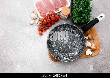 Padella in marmo nero con prodotti su sfondo grigio del tavolo, vista dall'alto Foto Stock