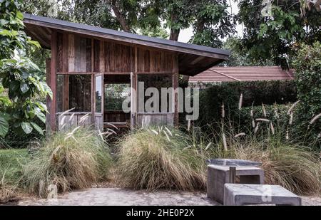 Bella piccola capanna di legno. Verde giardino gioia in estate con pietra e pianta di ryegrass perenne. Rilassatevi in giardino e godetevi il bel tempo. Foto Stock