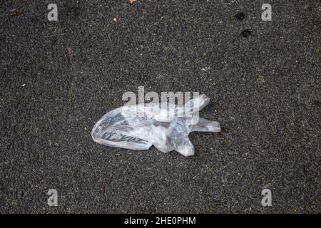 Guanto in plastica sottile monouso su asfalto. Guanto usato gettato in strada. Inquinamento ambientale dopo la quarantena. Rifiuti di plastica ecologici Foto Stock