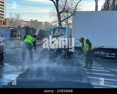 Gli operai della città catalizzano la superficie della strada dopo aver completato la sostituzione del tubo sotterraneo al mattino presto lungo Caton Avenue all'Ocean Parkway a Brooklyn, New York. Foto Stock