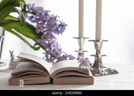libro aperto e due candele su un tavolo con fiori di primavera Foto Stock