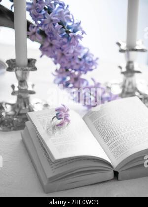 libro aperto e due candele su un tavolo con fiori di primavera Foto Stock