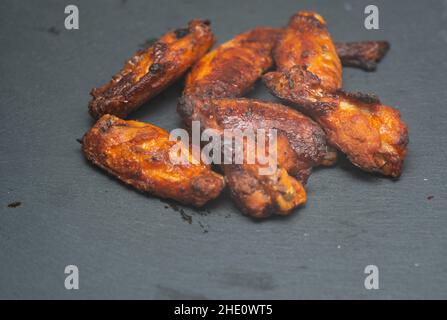 ali di pollo piccanti in primo piano su cottura in ghisa. Foto Stock