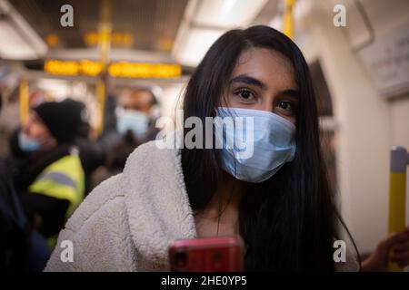 La ragazza indossa una maschera facciale e viaggia all'interno della metropolitana di londra. Uso della maschera chirurgica sui trasporti pubblici nella capitale inglese. Londra sotto gound Foto Stock