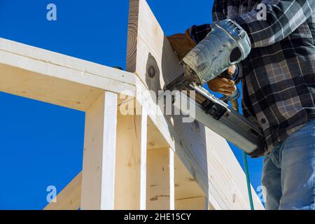 Un carpentiere per chiodare travi di legno con un martello pneumatico Foto Stock