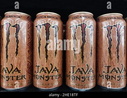 Houston, Texas USA 01-06-2022: Bombolette di bevanda energetica Java Monster allineate su uno scaffale del supermercato con uno sfondo nero. Foto Stock