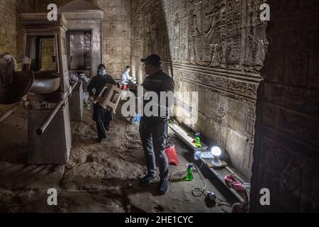 Restauratori conservatori che lavorano per riparare e ripristinare antiche pareti in pietra egiziana ricoperte di geroglifici e sculture in rilievo in un sito storico. Foto Stock