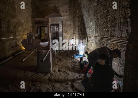 Restauratori conservatori che lavorano per riparare e ripristinare antiche pareti in pietra egiziana ricoperte di geroglifici e sculture in rilievo in un sito storico. Foto Stock