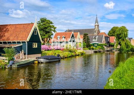 Pittoresco idilliaco villaggio di De Rijp in Olanda del Nord, Olanda, vista di caratteristiche case in legno con tetti di tegole rosse e aiuole di fiori e il c Foto Stock