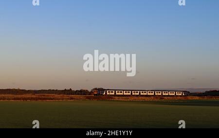 Mercoledì 5.1.22 l’unità flex della Northern n. 769450 attraversa il tappeto erboso del West Lancashire, che cresce pianeggiante sotto un grande cielo su Bescar Moss. Foto Stock