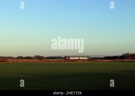 Mercoledì 5.1.22 il treno diesel n. 156 452 della Northern attraversa il tappeto erboso del West Lancashire, che cresce pianeggiante sotto un grande cielo su Bescar Moss. Foto Stock