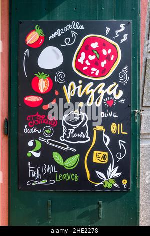 Lavagna pubblicitaria dipinta a mano per la pizza accanto ad una porta del ristorante. Foto Stock