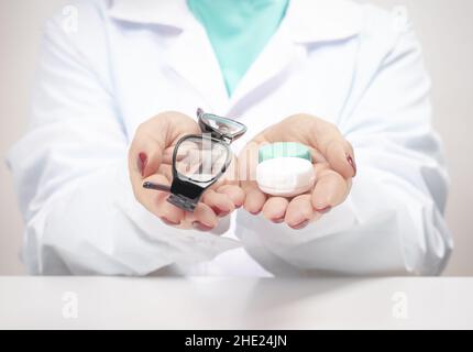 Medico oftalmologo che tiene gli occhiali e le lenti a contatto. Scelta tra lenti a contatto o occhiali. Correzione della vista. Oftalmologia, eccellente v Foto Stock