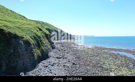 Immagine aerea della costa gallese e della scogliera a Llannon, Cerediaion. Cielo blu e mare, spiaggia di ciottoli, sentiero costiero. Foto Stock