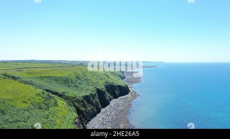 Immagine aerea della costa gallese e della scogliera a Llannon, Cerediaion. Cielo blu e mare, spiaggia di ciottoli, sentiero costiero. Foto Stock