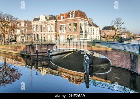 Leiden, Paesi Bassi, 16 dicembre 2021: Scenario pittoresco nella città vecchia, con un ponte e case tradizionali che si riflettono nelle acque di un canale Foto Stock