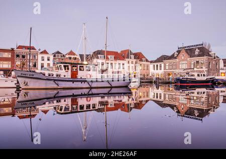 Leiden, Paesi Bassi, 16 dicembre 2021: Scenario pittoresco nella città vecchia con case storiche e barche che relfecting nelle acque del Vecchio Reno Foto Stock