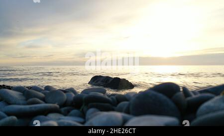 Immagine scattata da un drone su una spiaggia di ciottoli che si affaccia sul mare al tramonto. Foto Stock