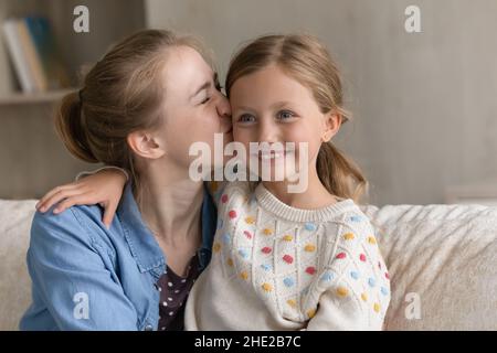 Giovane madre affettuosa che bacia la bambina a casa. Foto Stock