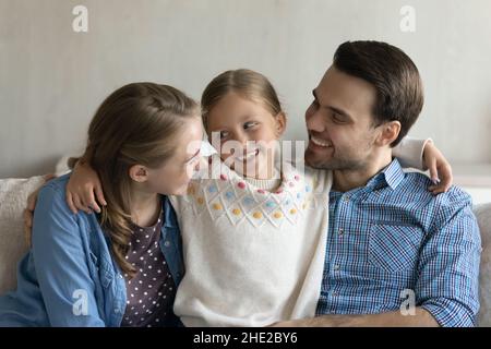 Felice adorabile ragazzina che comunica con i genitori gioiosi. Foto Stock