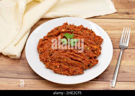 Pasta al peperoncino su sfondo ligneo. Pasta piccante. Una sorta di adjika. Antipasti di cucina turca. Vista orizzontale. Primo piano Foto Stock