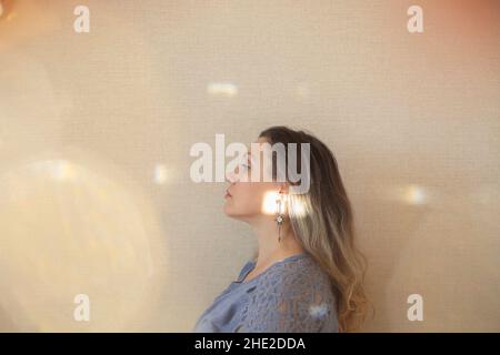 Amatevi ad ogni età. Donna di mezza età di 50s anni che tocca delicatamente il mento con la mano e guarda la macchina fotografica mentre si posa isolato su sfondo beige chiaro Foto Stock