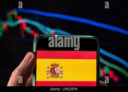 Cina. 09th Dic 2021. In questa illustrazione della foto la bandiera del Regno di Spagna visto su uno smartphone con un grafico di indice di borsa economica sullo sfondo. (Foto di Budrul Chukrut/SOPA Images/Sipa USA) Credit: Sipa USA/Alamy Live News Foto Stock