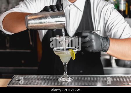 Barista professionista con uno shaker nelle sue mani che fa un cocktail alcolico Margarita. Foto Stock