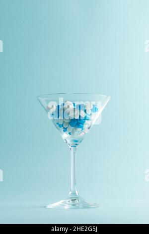 Layout creativo con bicchiere martini pieno di pillole blu. Concetto minimo. Foto Stock