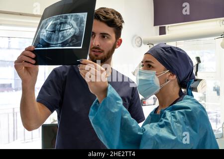 Due dentisti esperti di esame radiologico di una mandibola umana in studio dentistico Foto Stock