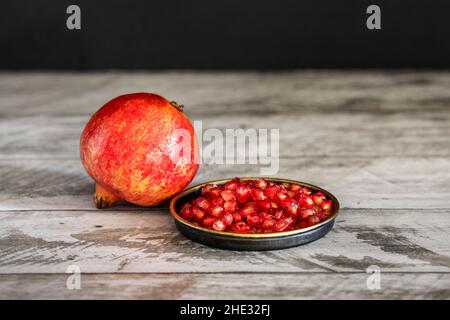 Melograno rosso con grani maturi su piastra di metallo d'annata Foto Stock