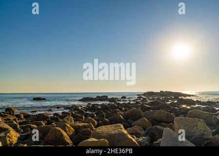 Splendida vista sul sole che brilla sul mare e sulla costa rocciosa Foto Stock