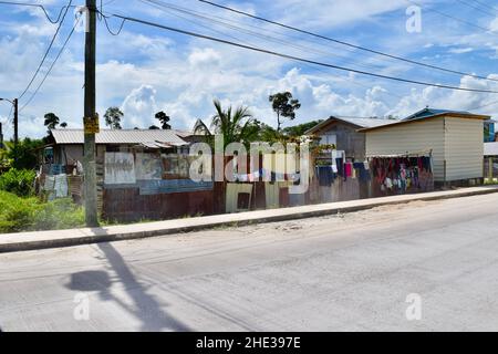 Vestiti che asciugano su una recinzione di foglio ondulato in un quartiere povero di Belize City, Belize. Foto Stock