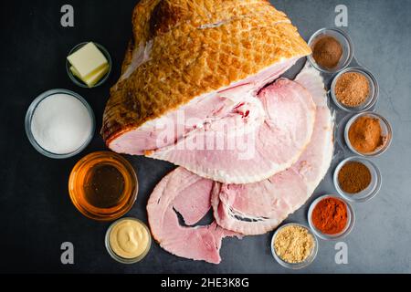 Ingredienti per un prosciutto glassato tagliato a spirale: Un prosciutto affumicato con miele, zucchero e spezie per fare uno smalto Foto Stock