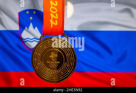 5 gennaio 2021, Pechino Cina. Medaglia d'oro dei XXIV Giochi Olimpici invernali sullo sfondo della bandiera slovena. Foto Stock