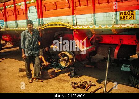 Meccanico camion in posa con il camion su cui sta lavorando all'aria aperta, Goa, India Foto Stock