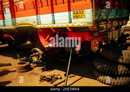 Meccanico camion in posa con il camion su cui sta lavorando all'aria aperta, Goa, India Foto Stock
