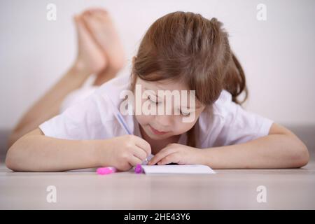 La bambina si trova sul pavimento e si disegna Foto Stock