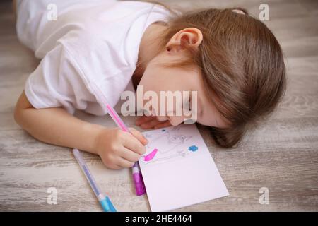 La bambina si trova sul pavimento e si disegna Foto Stock